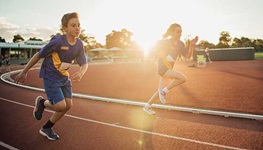 Two children running on a track field