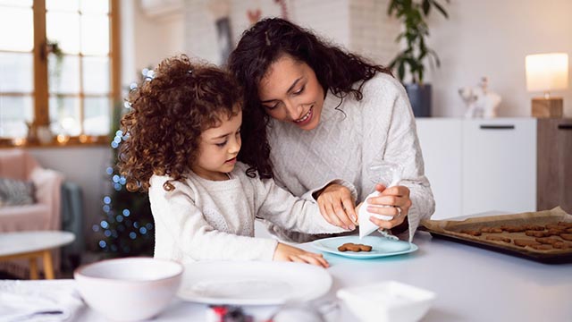 Mother and daughter decorating cookies in a bright kitchen