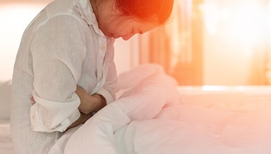 woman holding stomach in bed